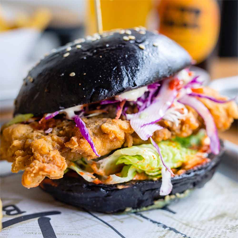A black-bun burger with crispy chicken and slaw