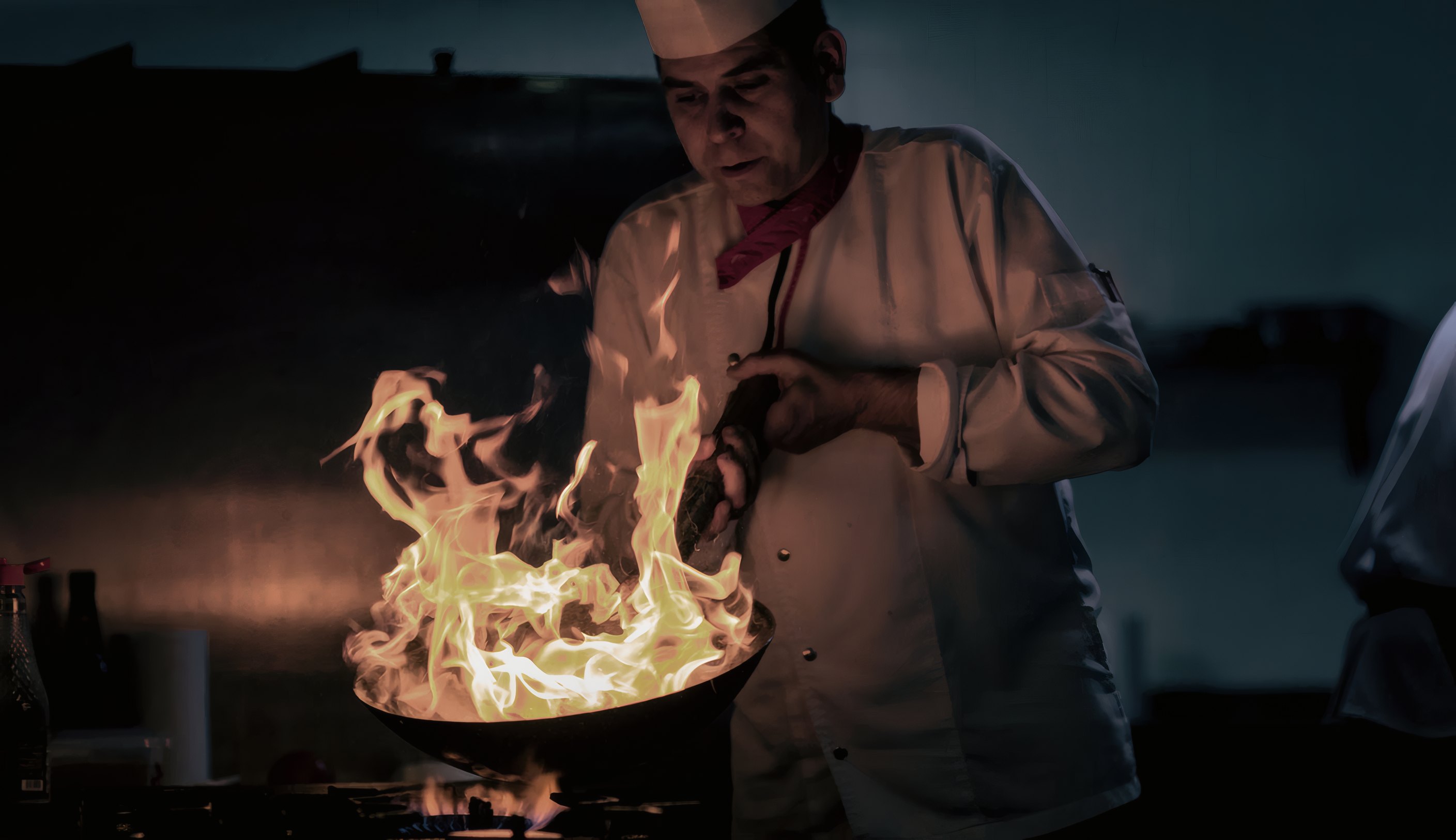 The grill master tossing a pan in a burst of flame