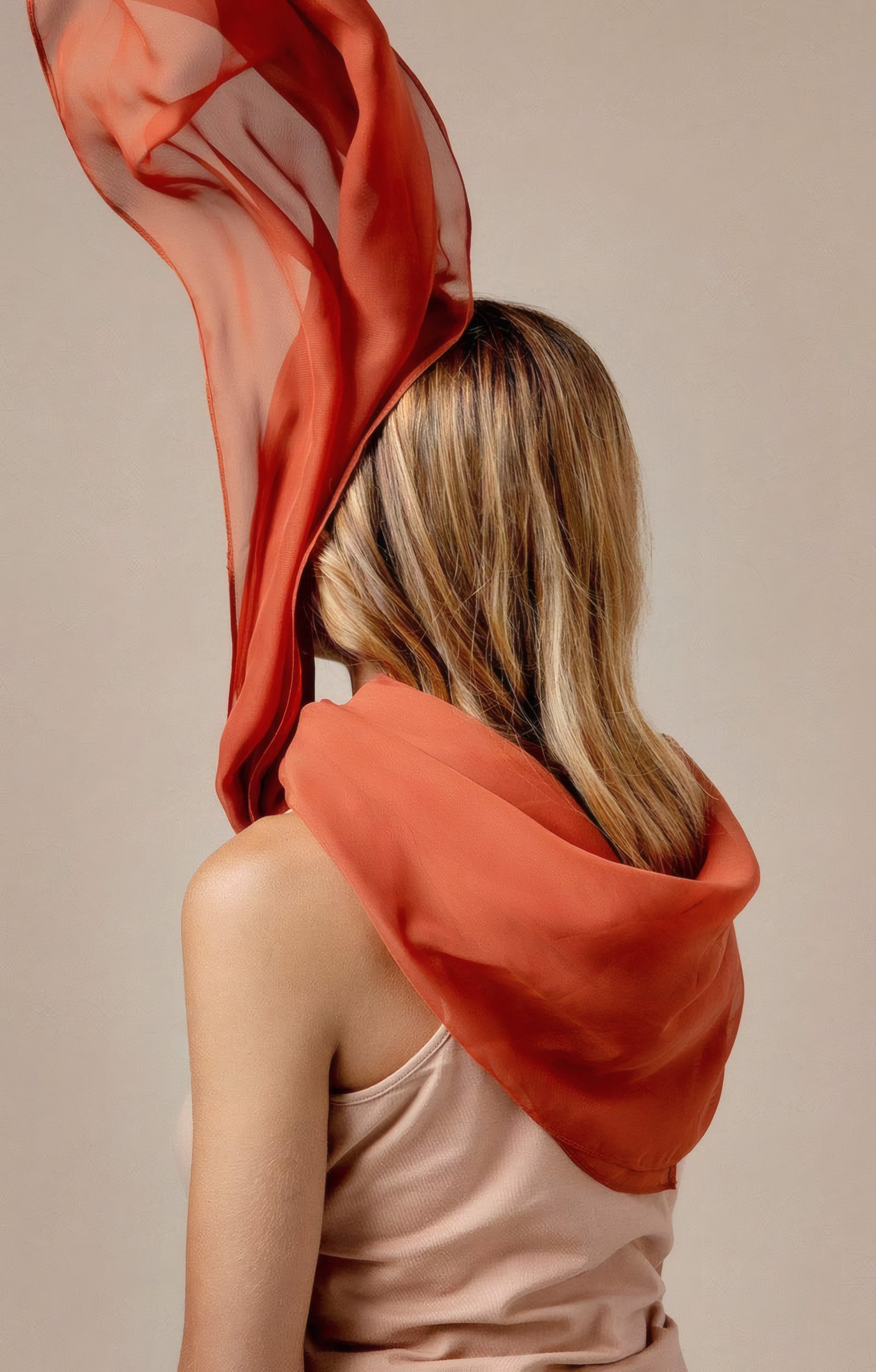 An orange silk scarf blowing from a woman's shoulders