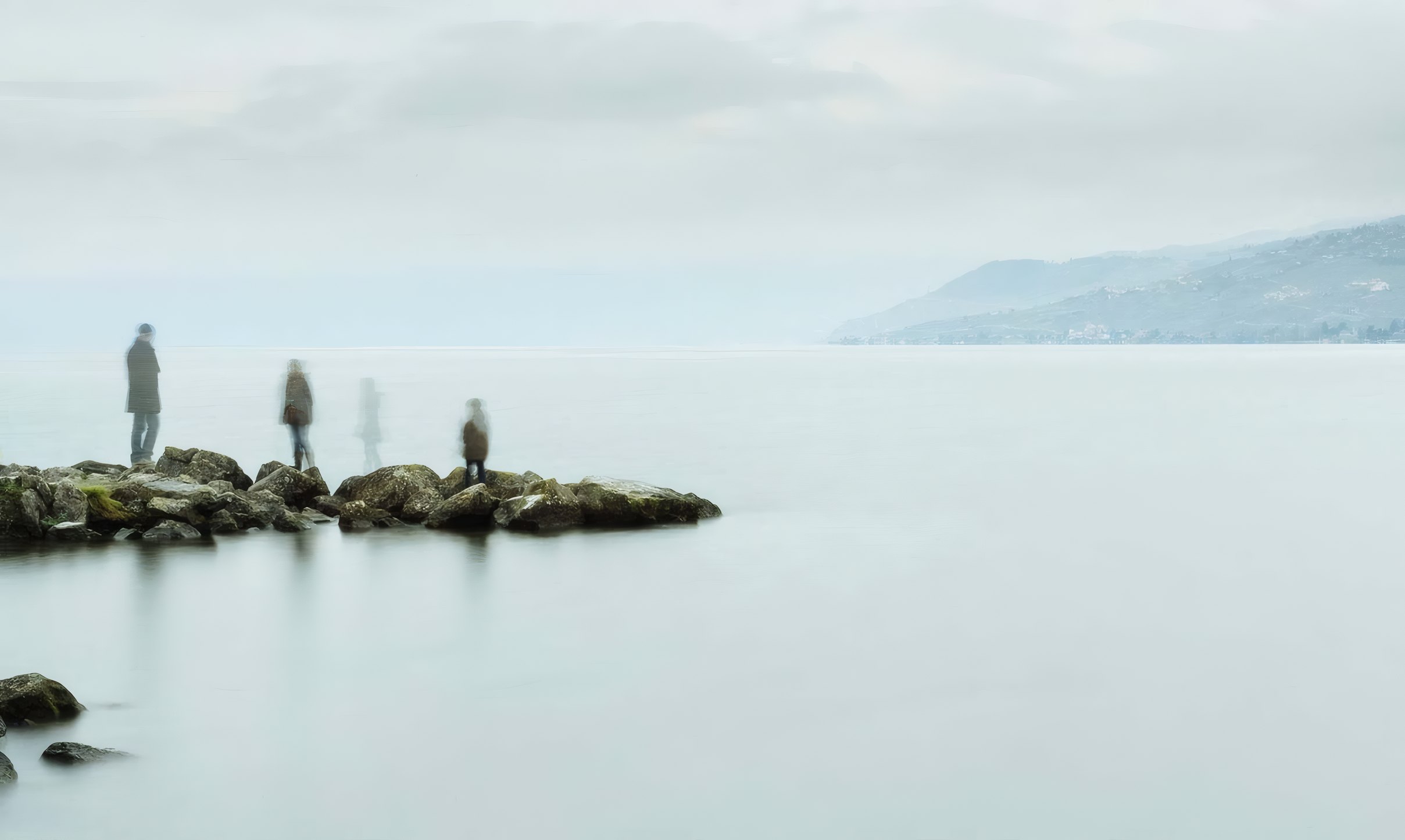 Stones and walkers in a still, misty loch