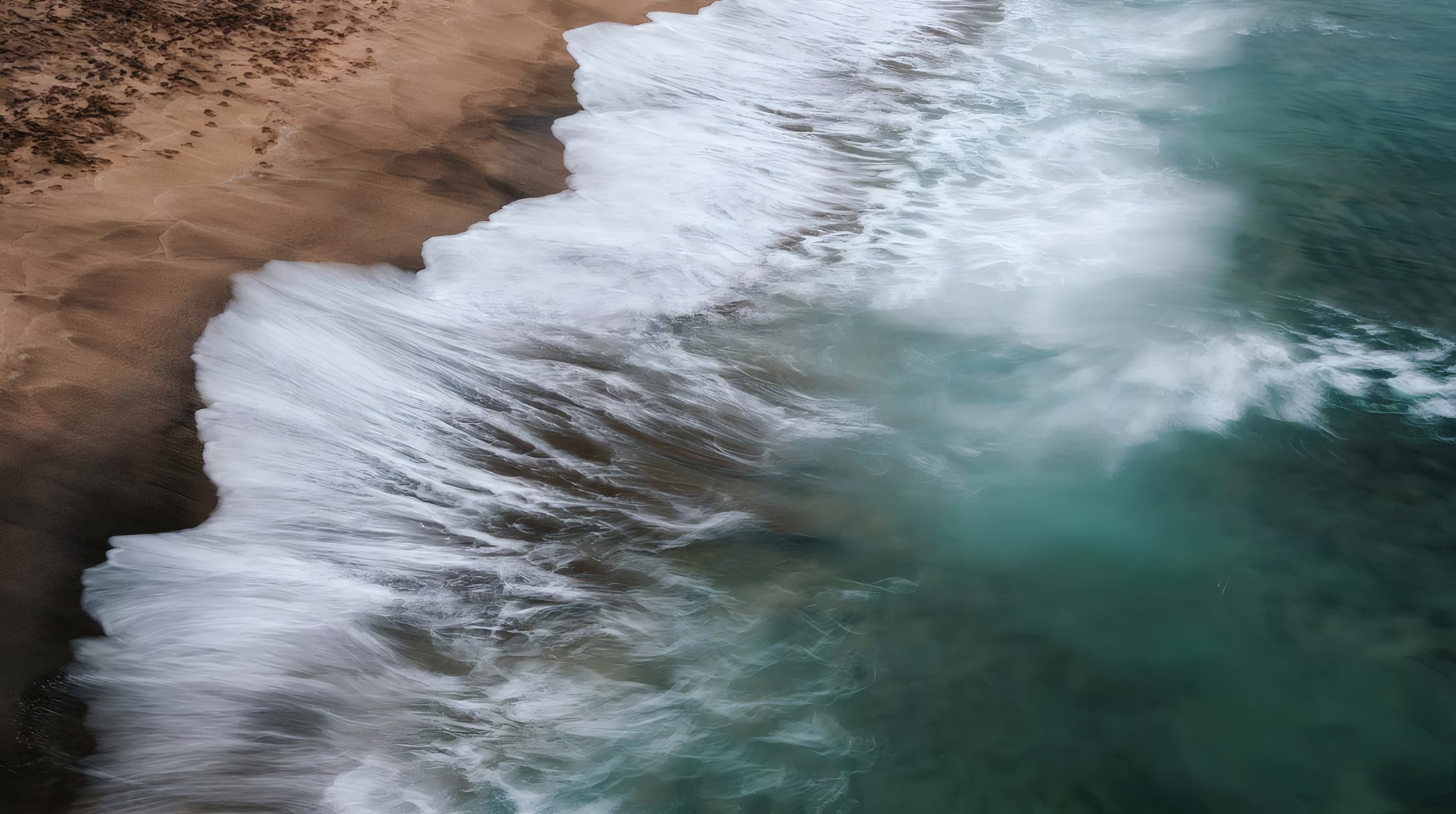 The tide rushing over dark sand