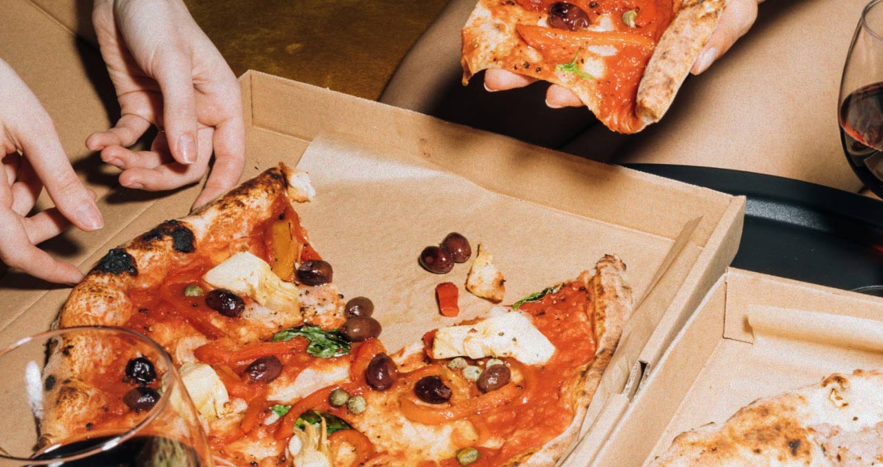 Hands lifting slices from an open pizza box
