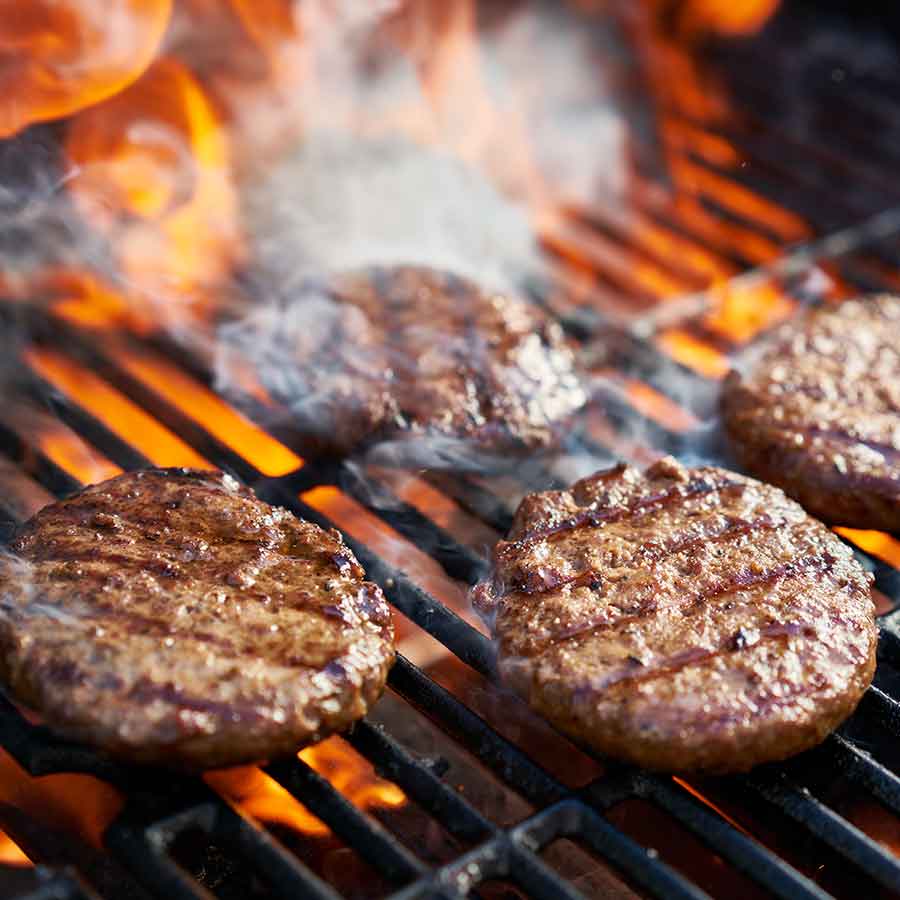 Beef patties searing over open flames