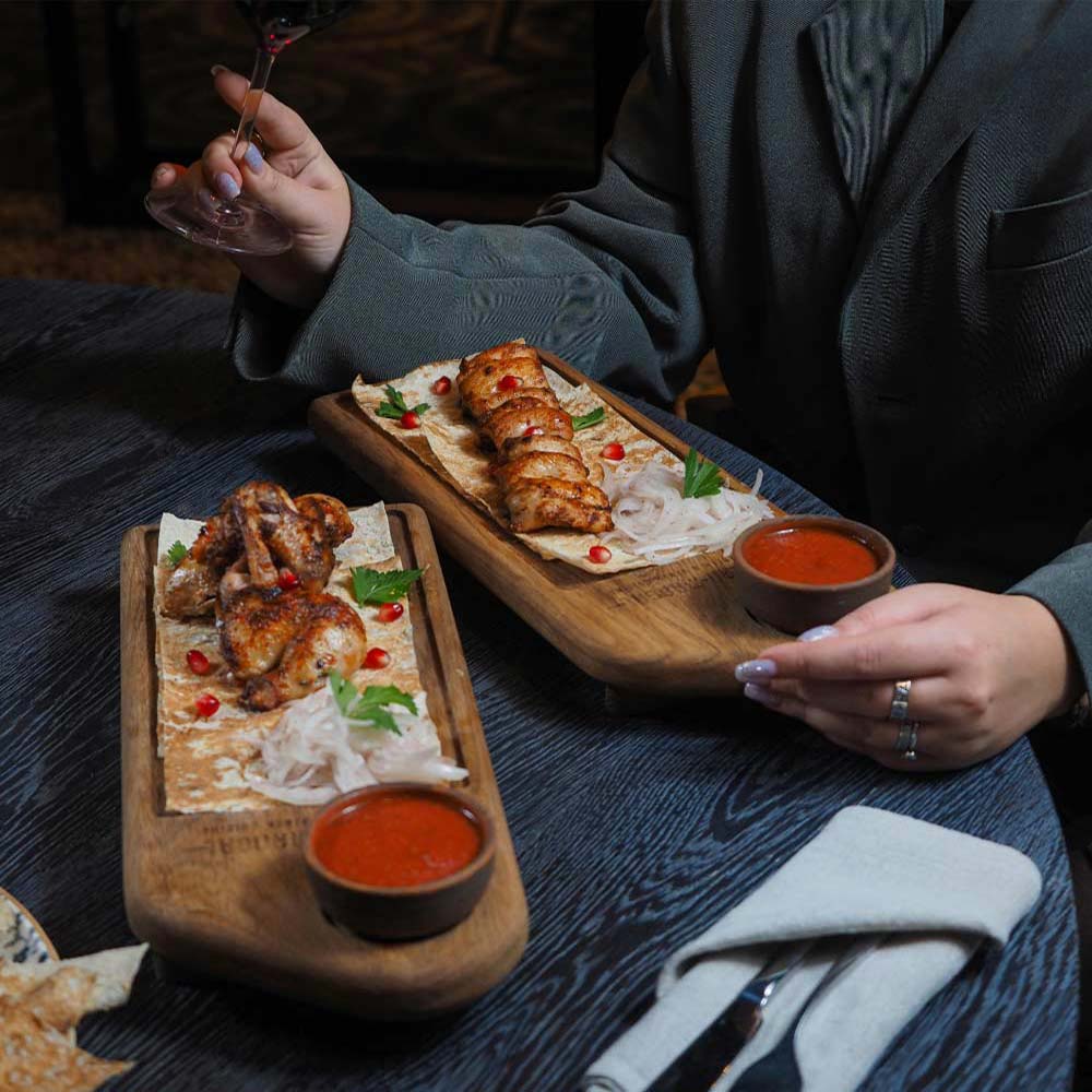 Hands reaching for plates of chicken and dips