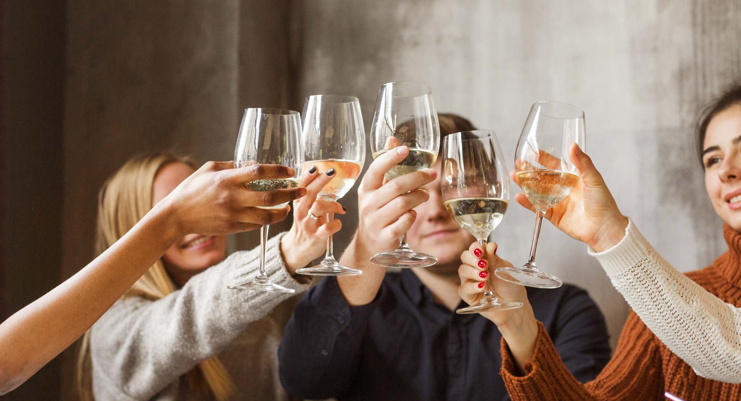 Friends raising glasses of white wine over the table