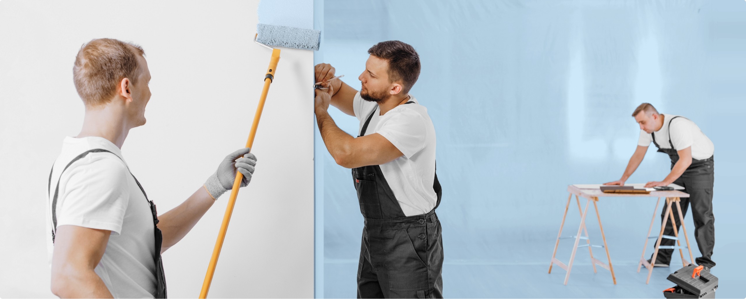 Two decorators painting a pale blue wall with a roller
