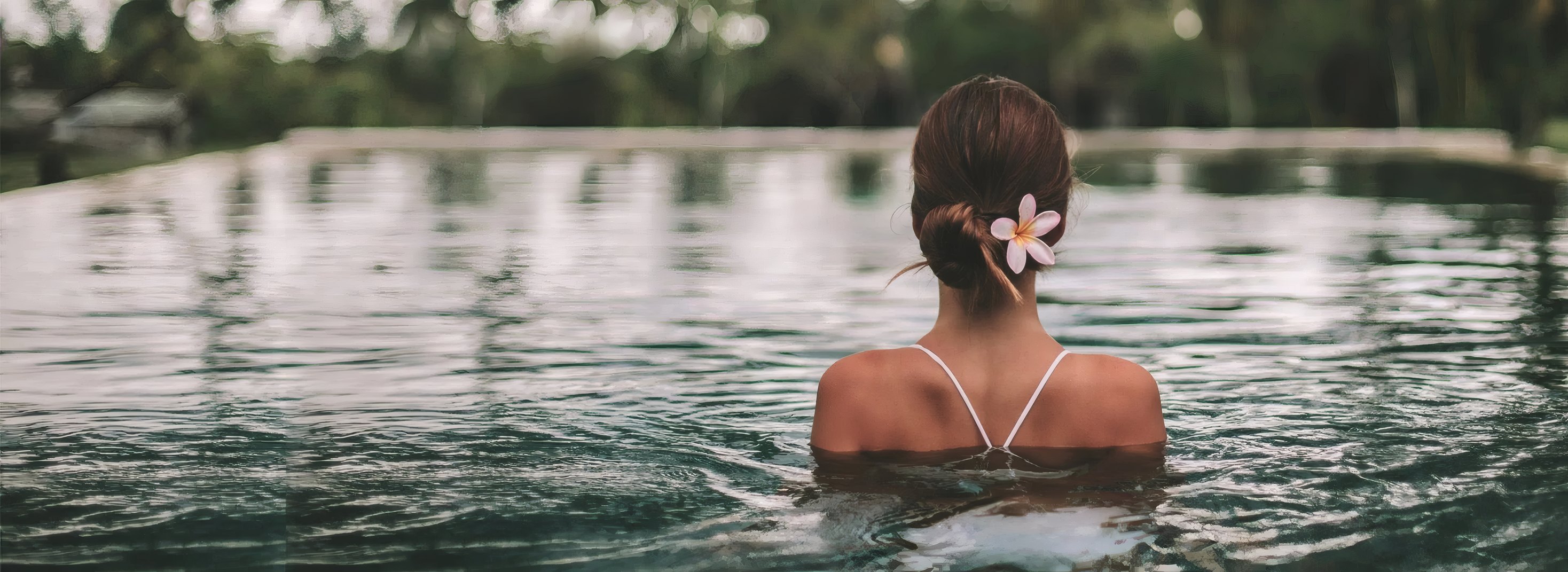 A guest in the infinity pool facing the jungle