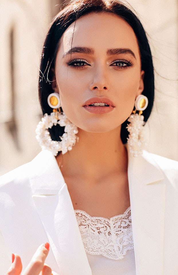 A client in a white blazer with flower earrings