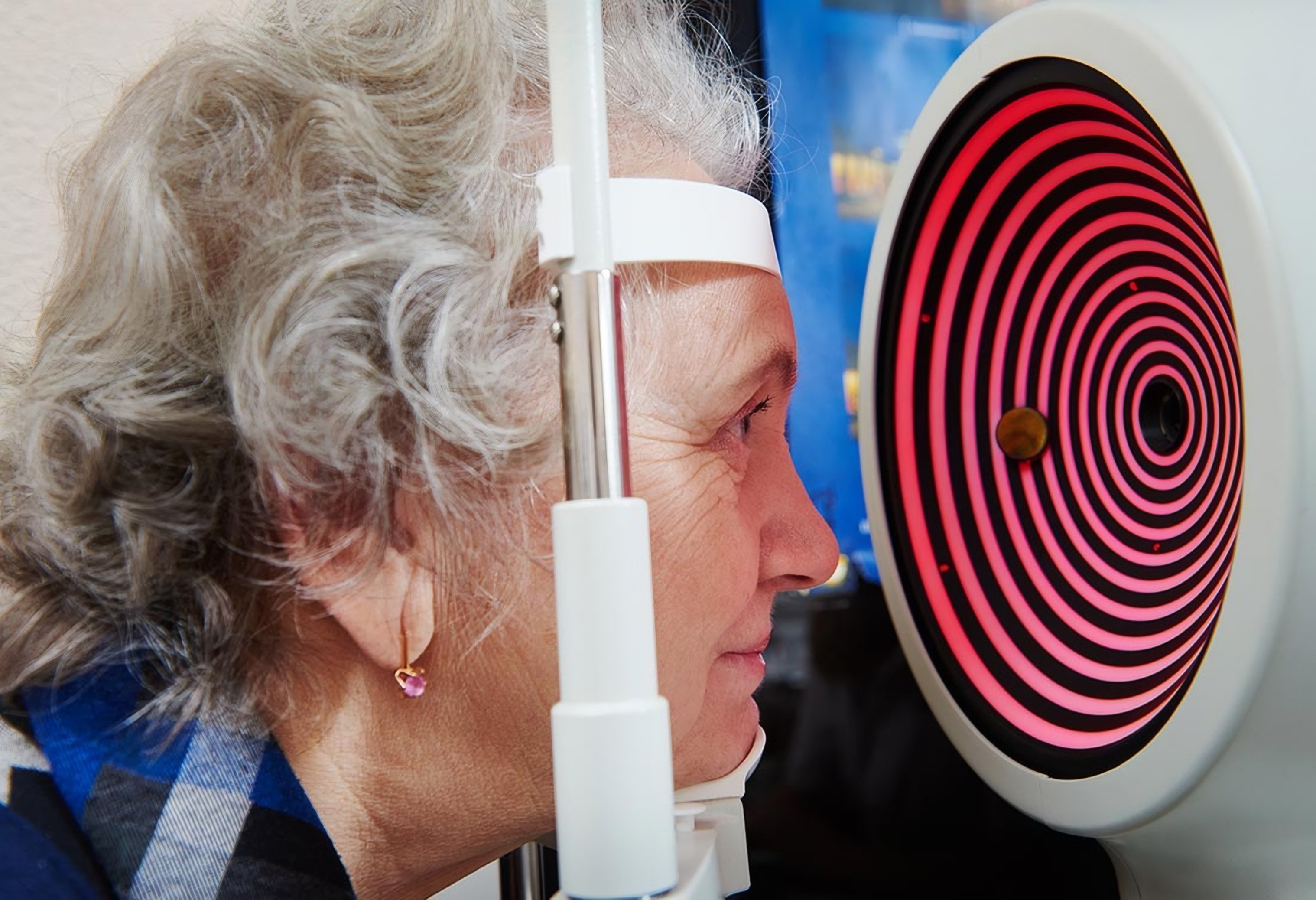 An optometrist tests an older woman's eyes