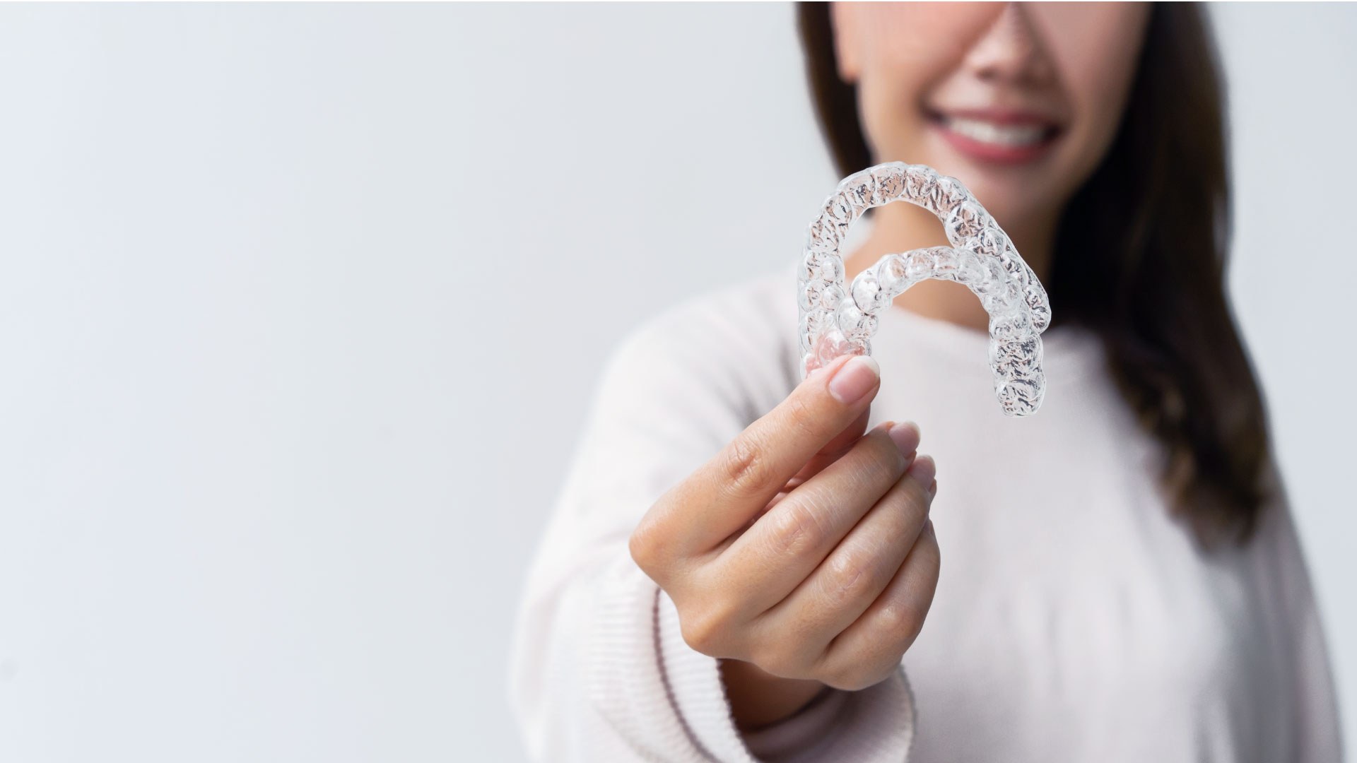 A woman holding a clear aligner