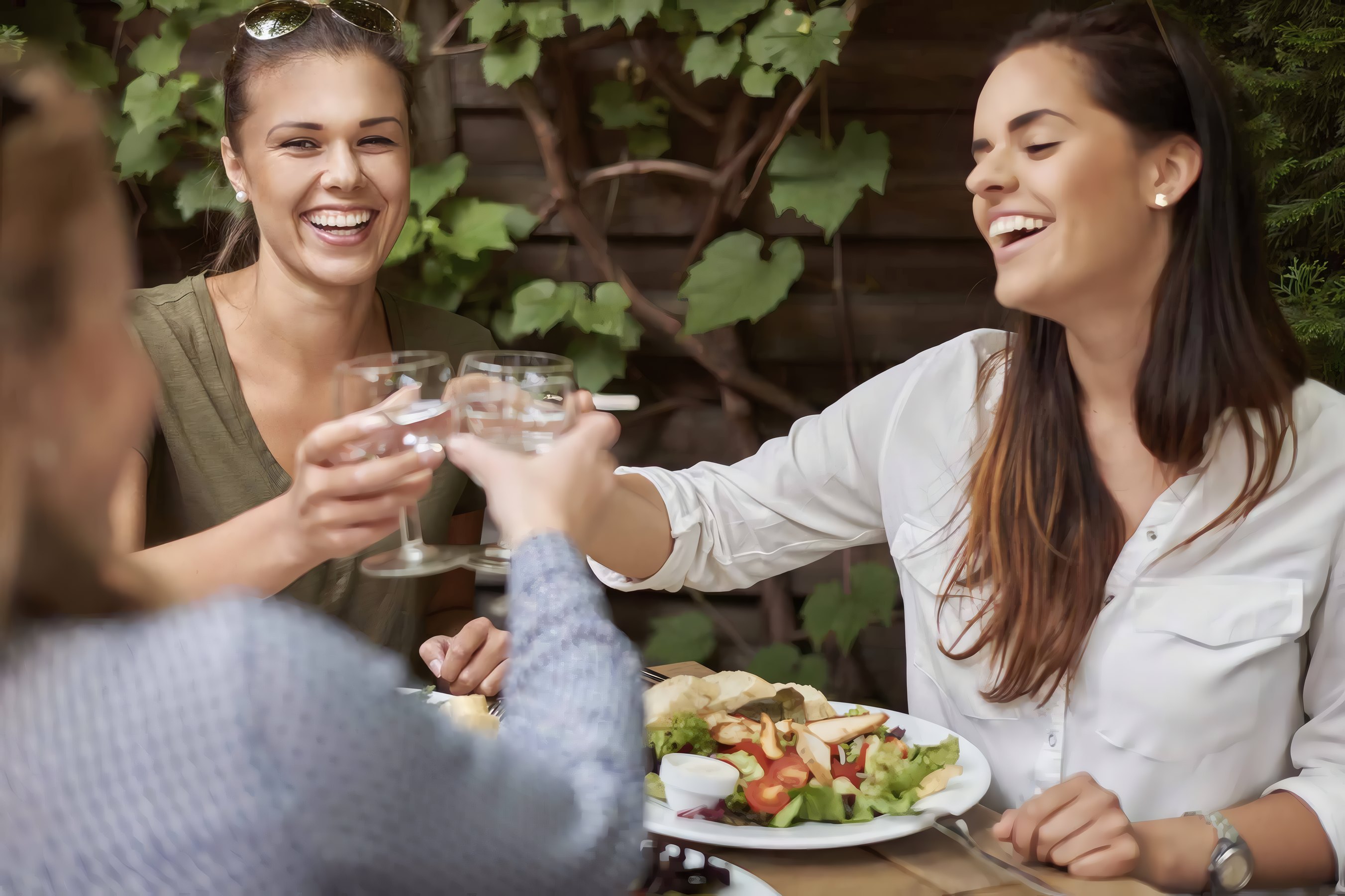 Two friends laughing over lunch at a table outdoors