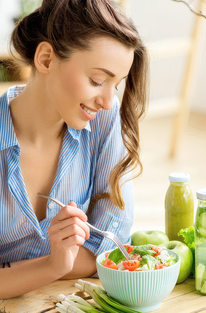 A woman eating a salad at a sunny table