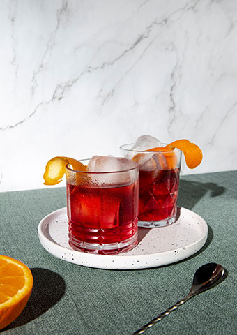 Two negronis on a white plate with an orange