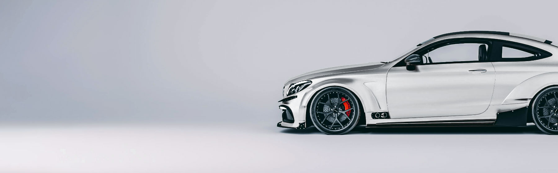 White coupe on wide alloy wheels in a studio