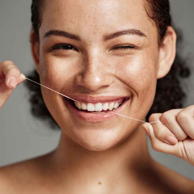 A smiling woman flossing