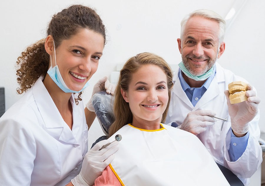 A dentist and his patient smiling in the chair