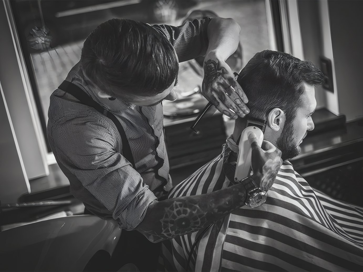 A barber cutting a client's hair under a striped cape