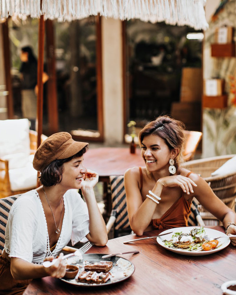 Two friends laughing over lunch on the terrace