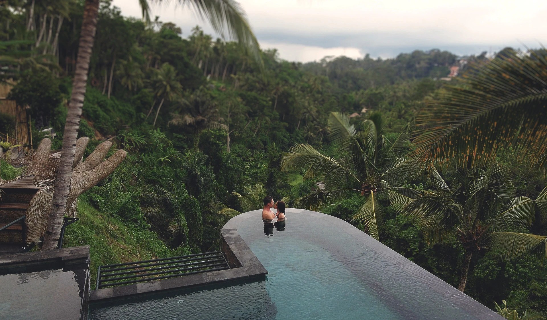Two guests in an infinity pool above the rainforest valley