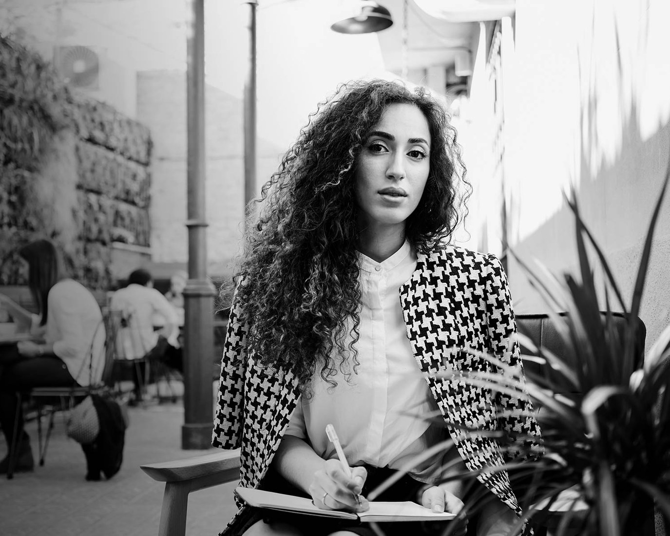 A new face with curly hair in a houndstooth jacket, in black and white