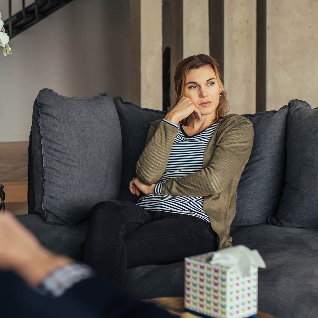 A client talking with her therapist on a grey sofa