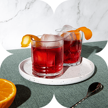 Two negronis with orange peel on a stone plate