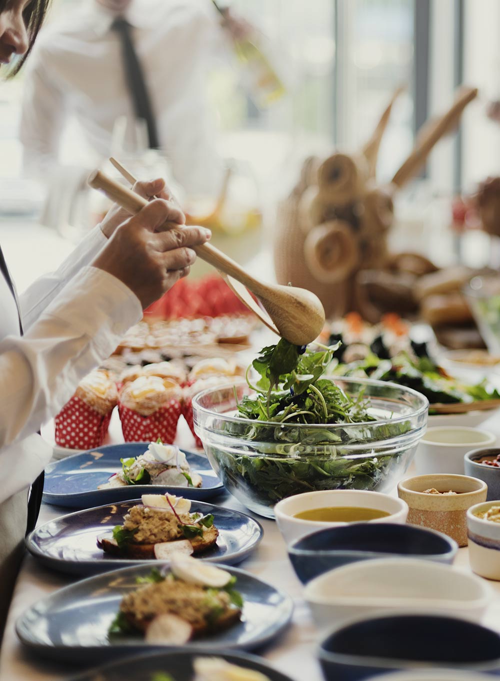 A chef finishing a salad at a long buffet