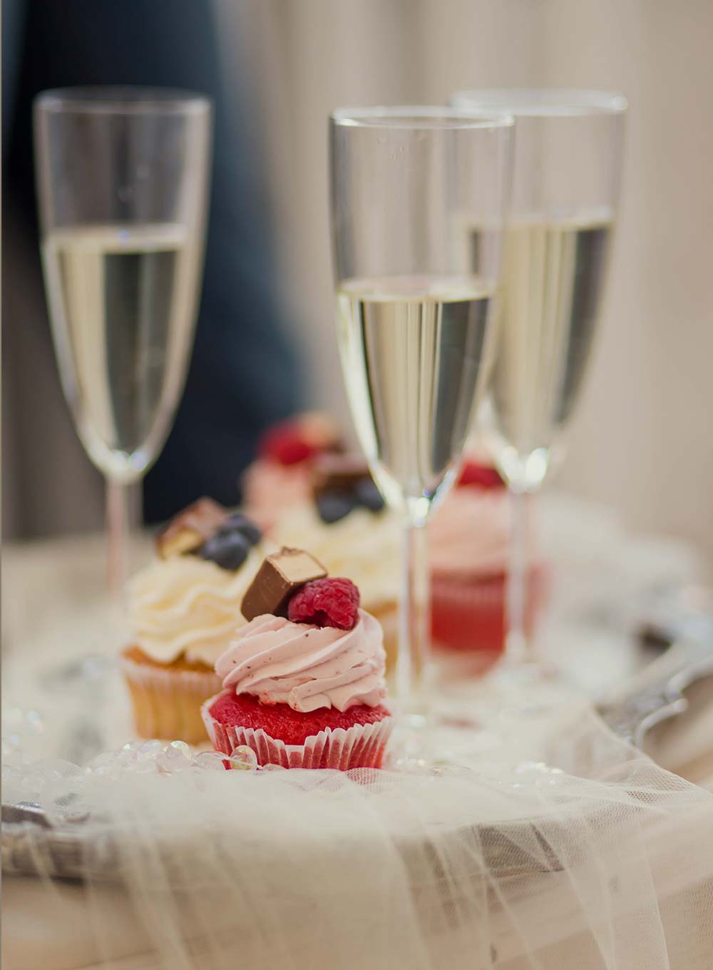 Champagne flutes and berry cupcakes on a dessert table