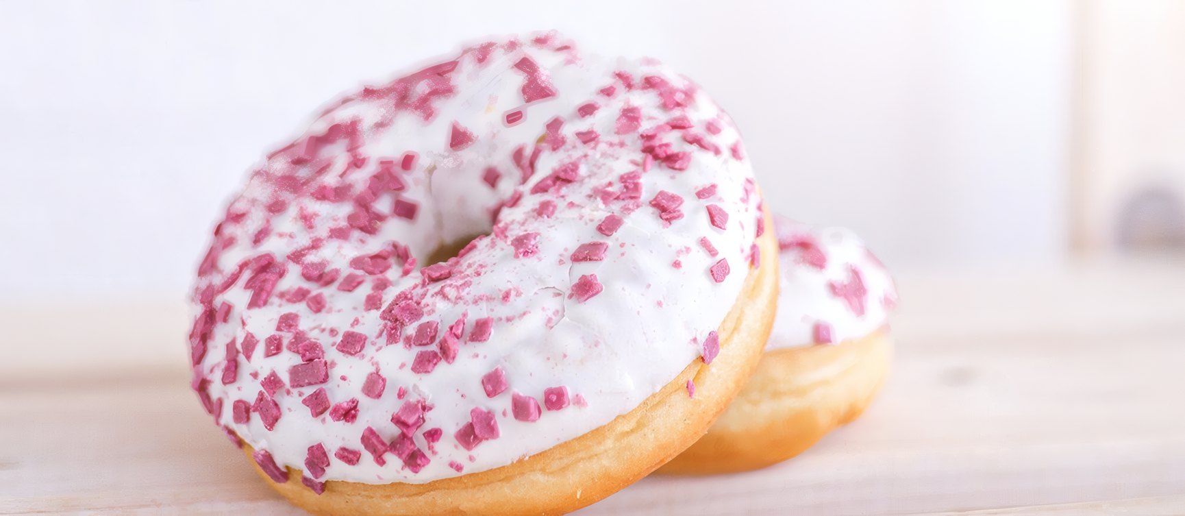 A pink glazed donut with sprinkles