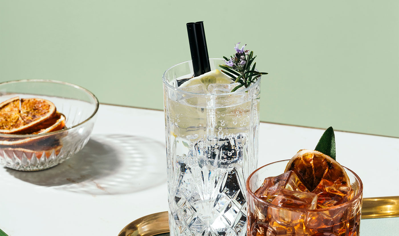 A tall gin highball with rosemary and grapefruit on a mint table