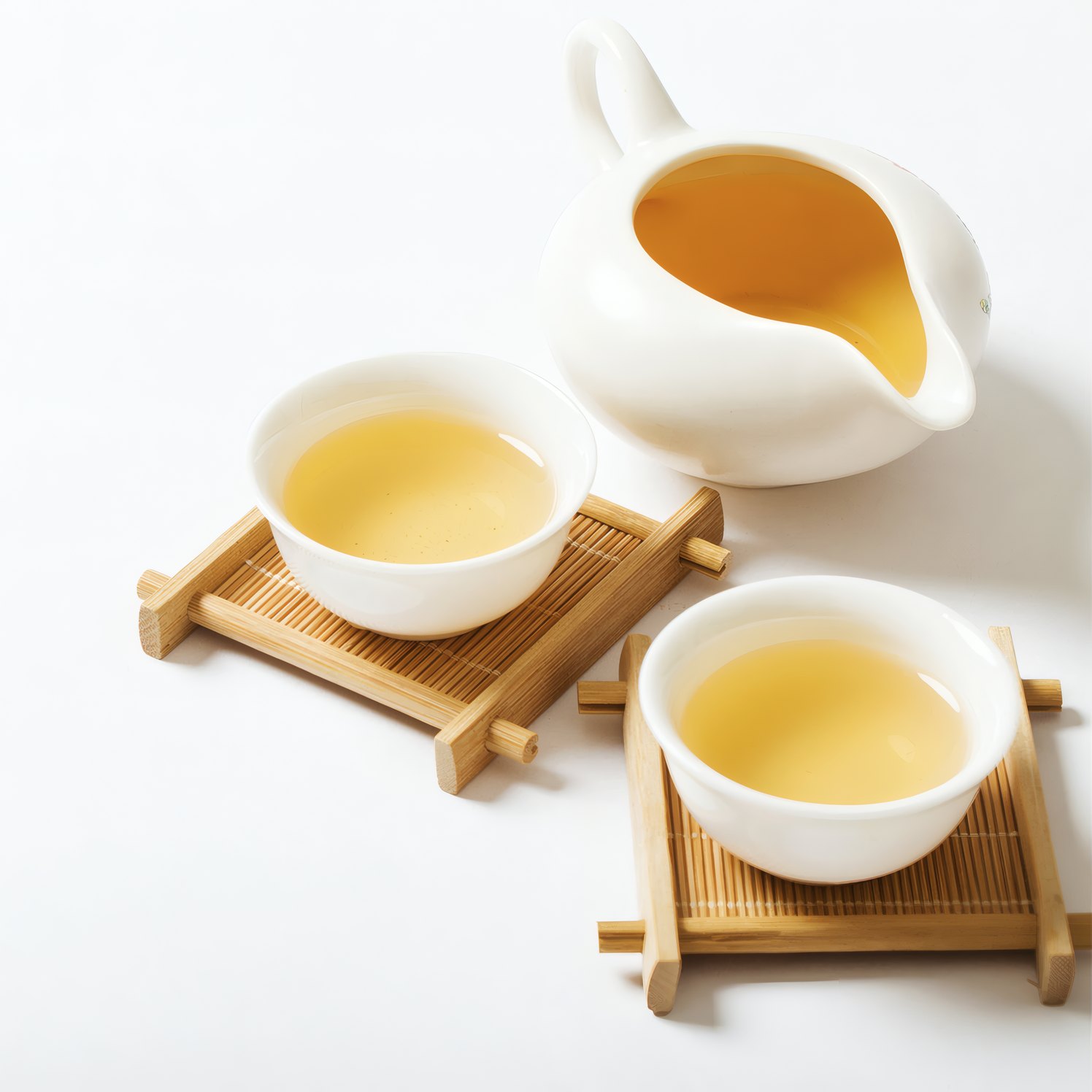 Two cups of tea on wooden coasters beside a jug