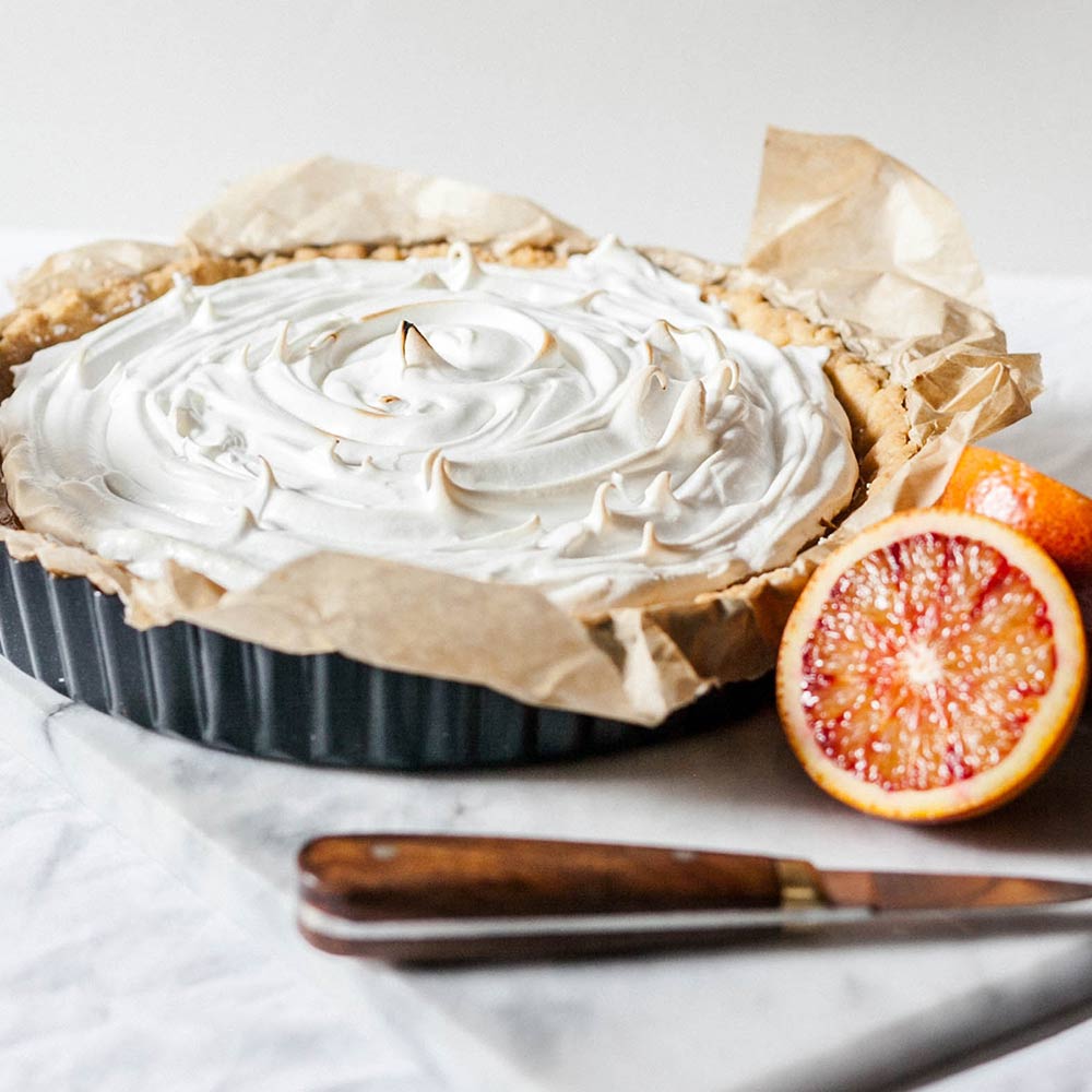 A meringue tart beside a blood orange