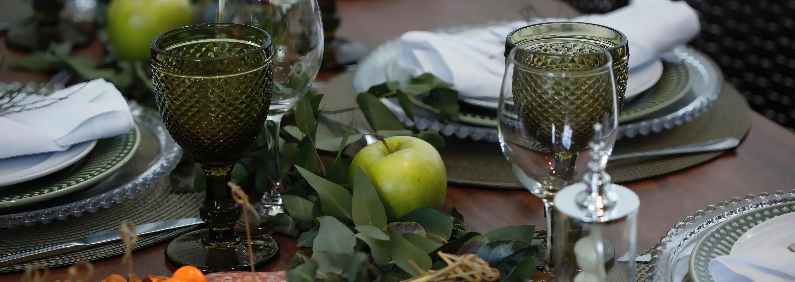 A long table laid with green glasses and linen