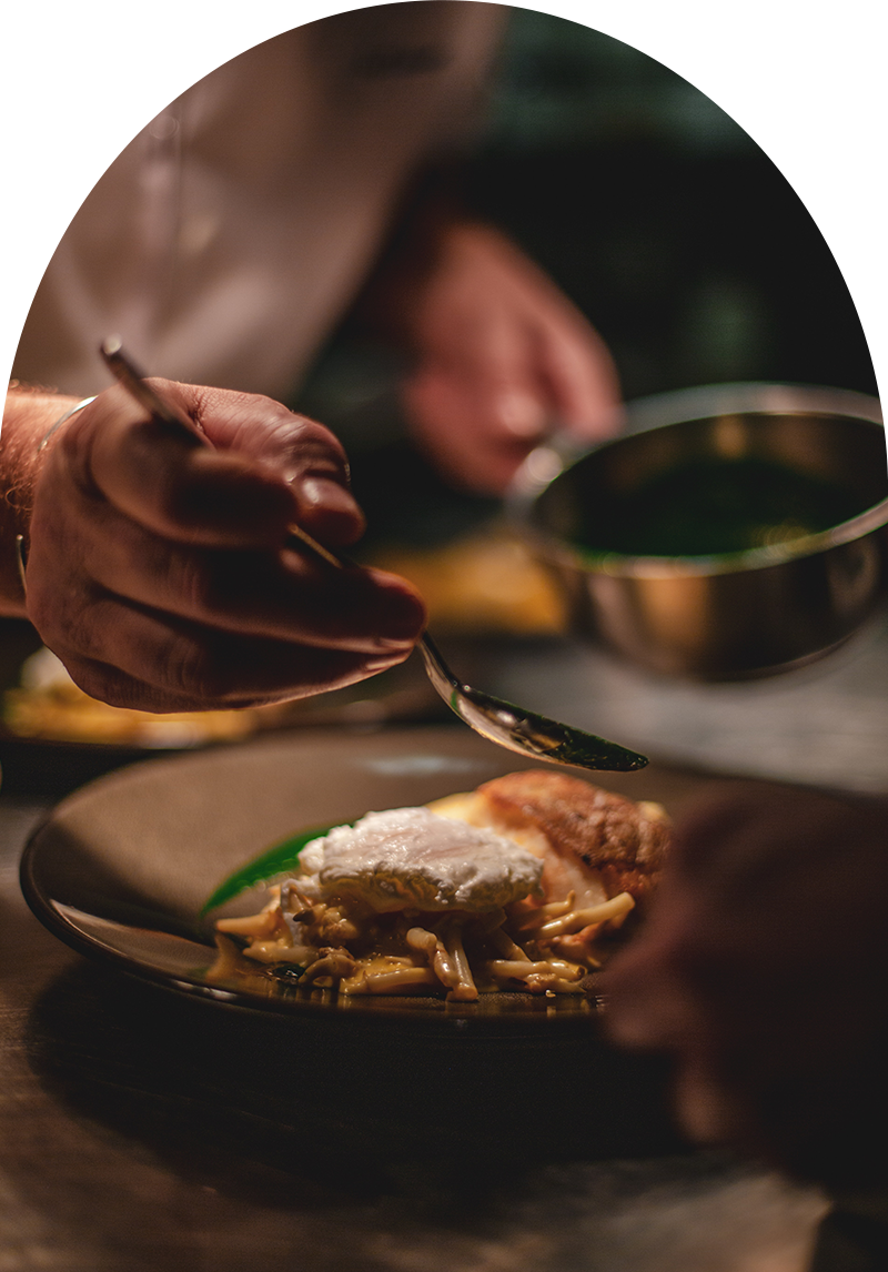 A chef spooning sauce over a plated dish