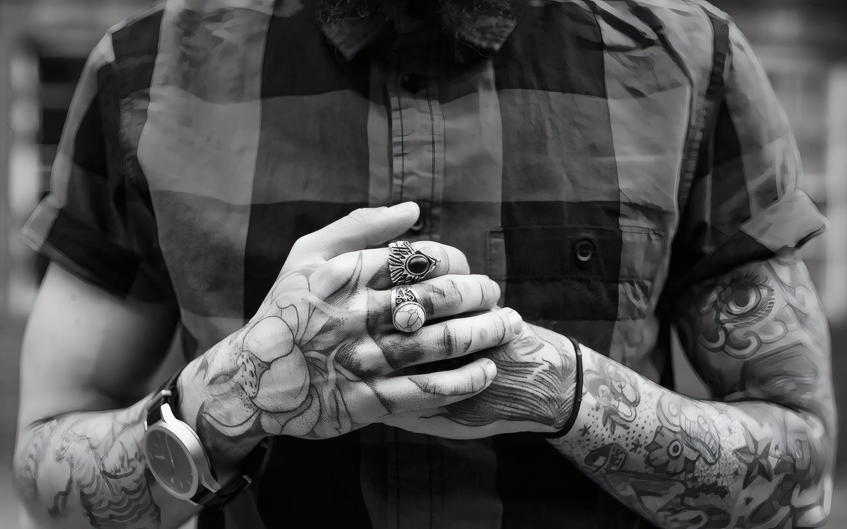 Tattooed hands with silver rings, clasped