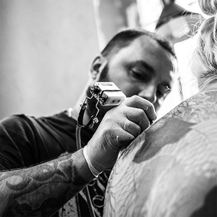 An artist tattooing a client's shoulder