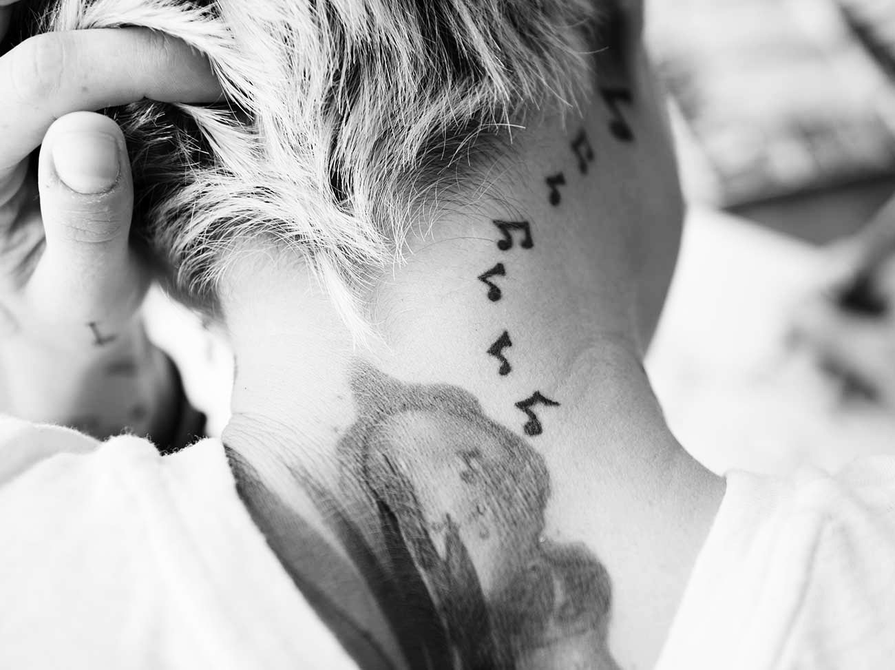 Small music-note tattoos behind an ear