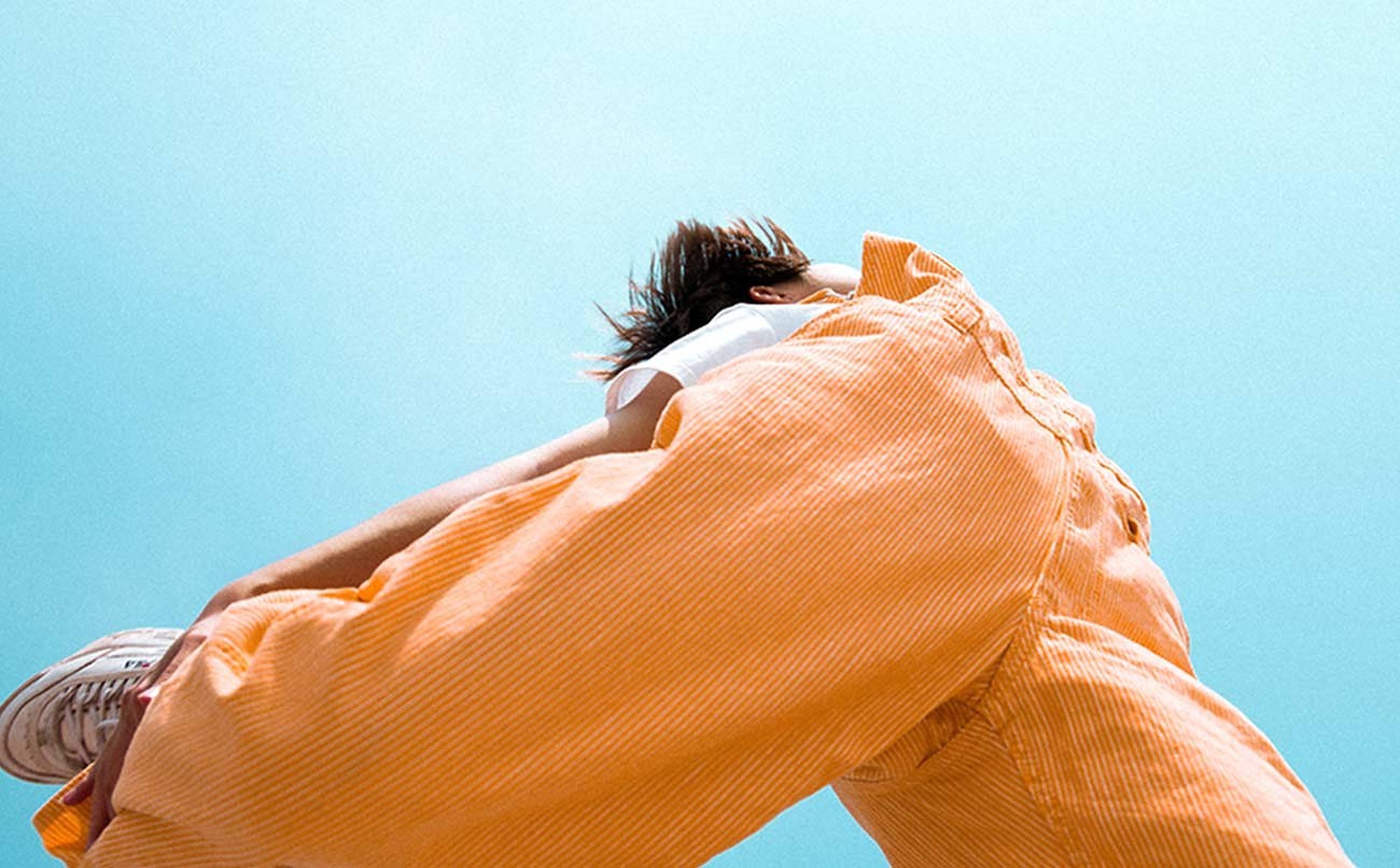 A woman in an apricot linen set against a clear sky