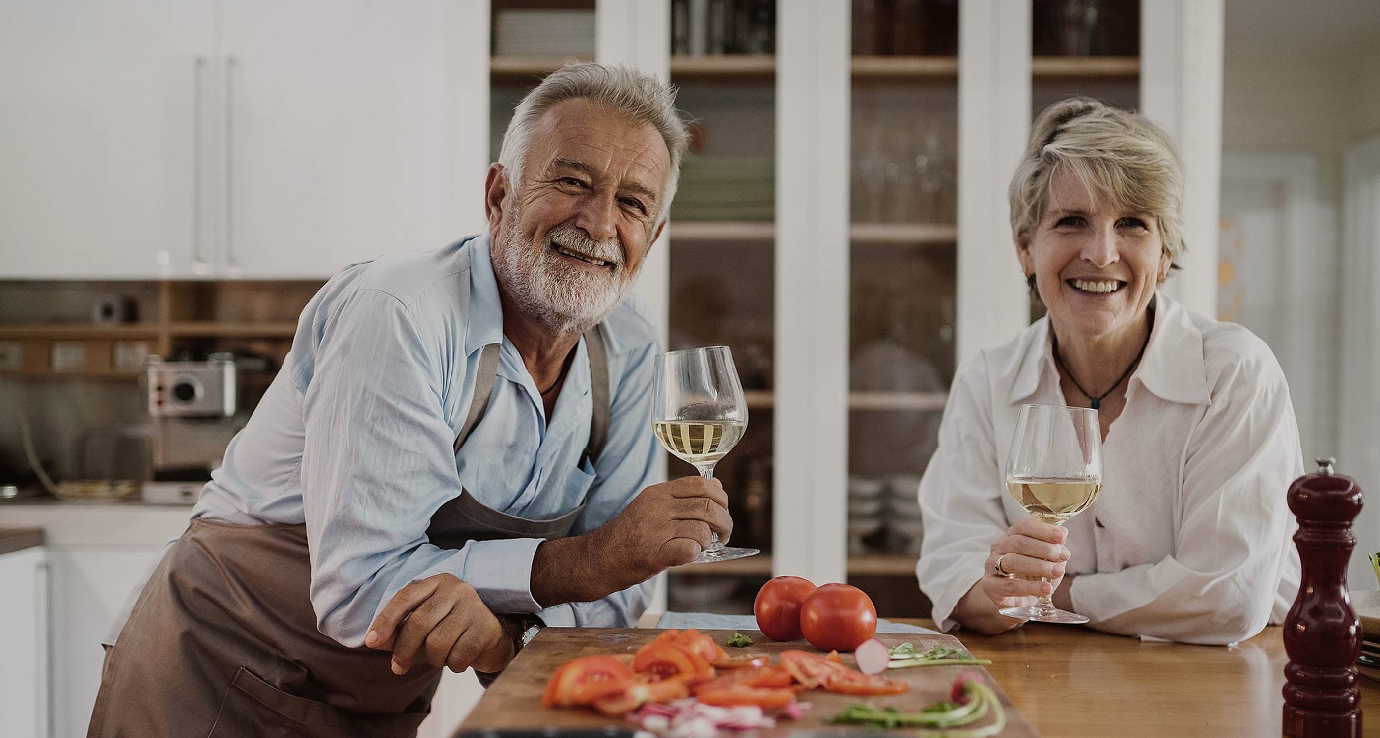 Two members laugh over a glass of white wine in the club kitchen