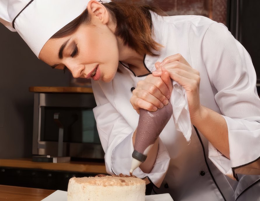 A chocolatier piping chocolate onto a cake