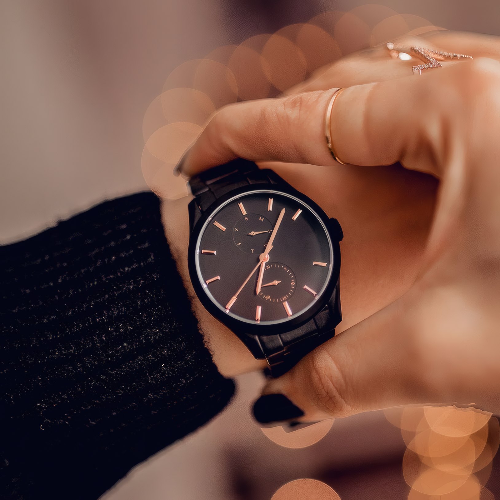A dark watch held in a hand in a black knit sleeve