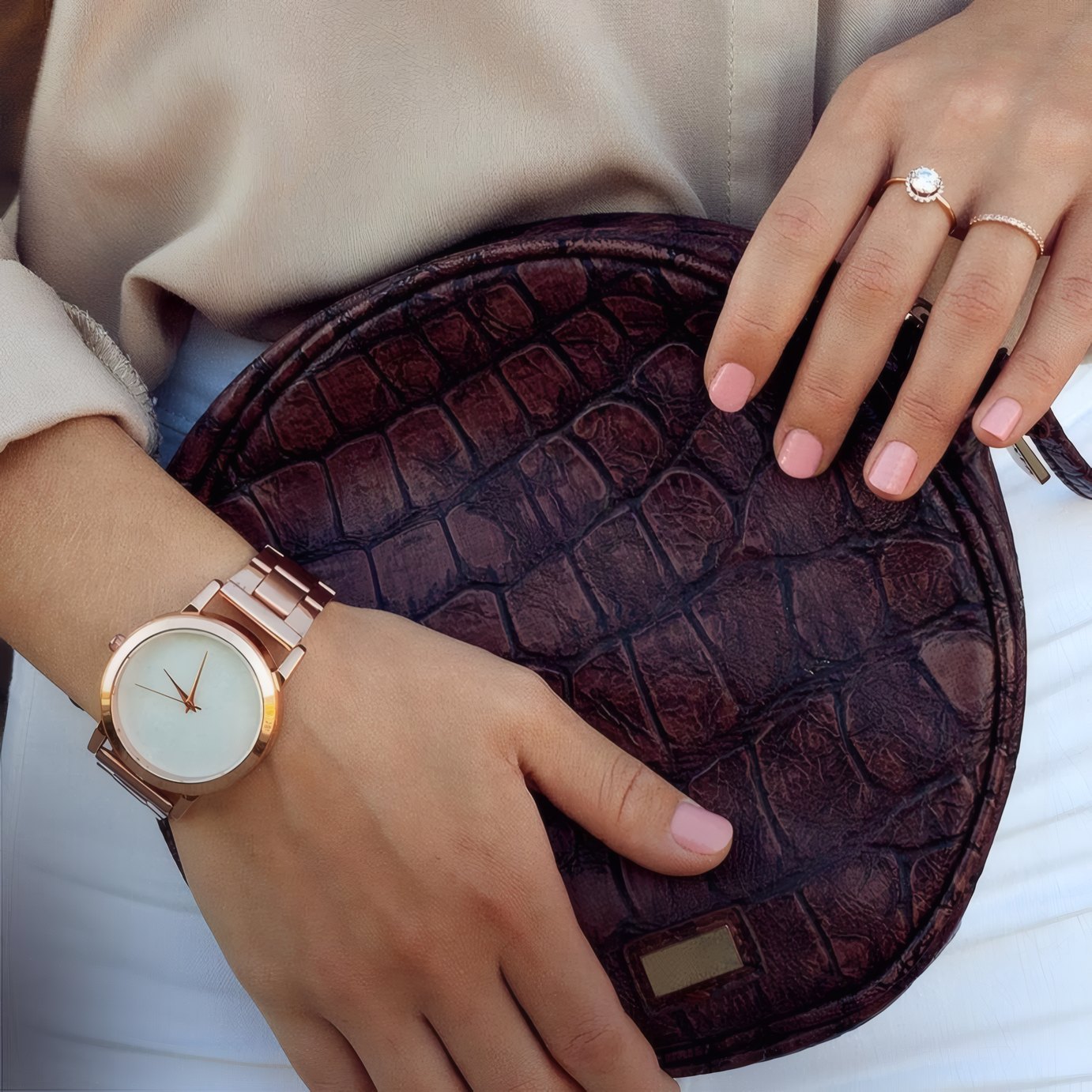 A rose gold watch beside a croc-embossed bag