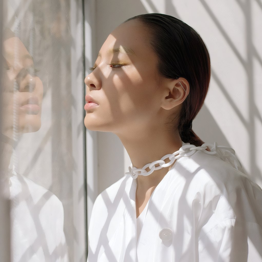 A woman in a white blouse by a sunlit window