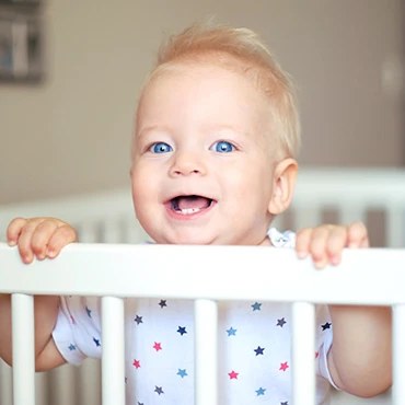Laughing baby standing in a cot