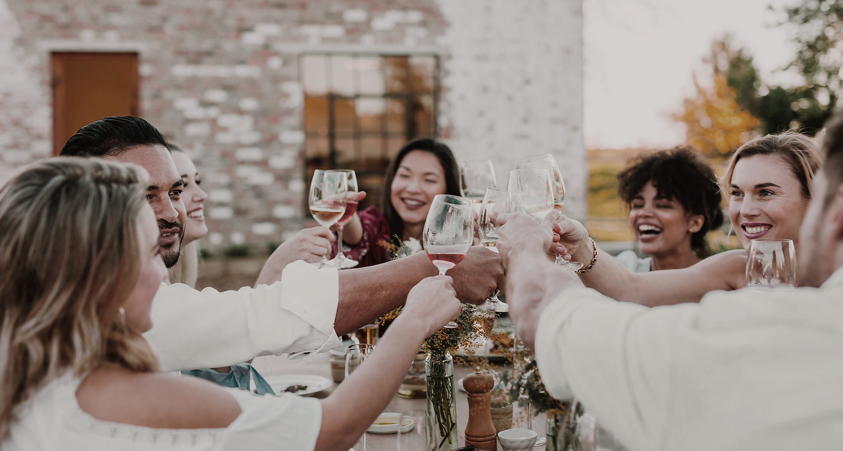Members raise their glasses at a long table outdoors