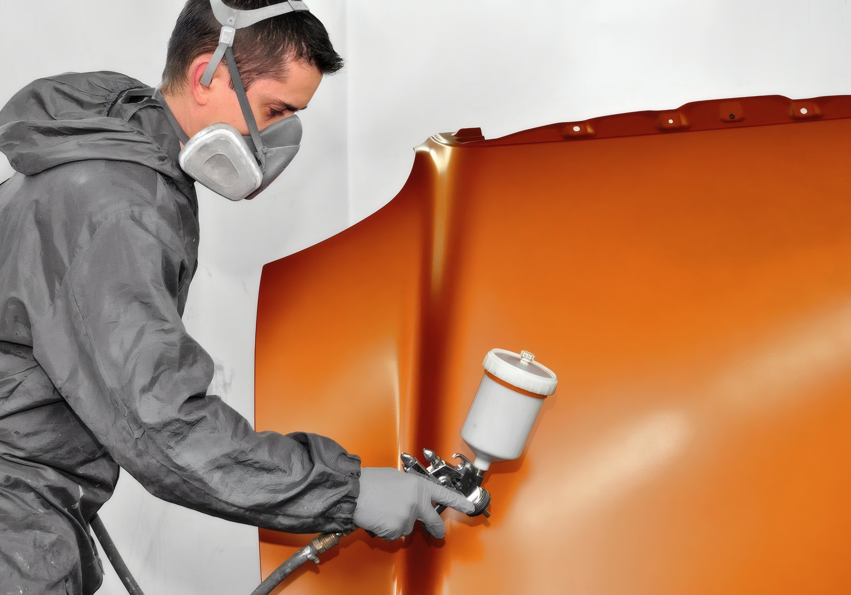 A painter spraying an orange panel
