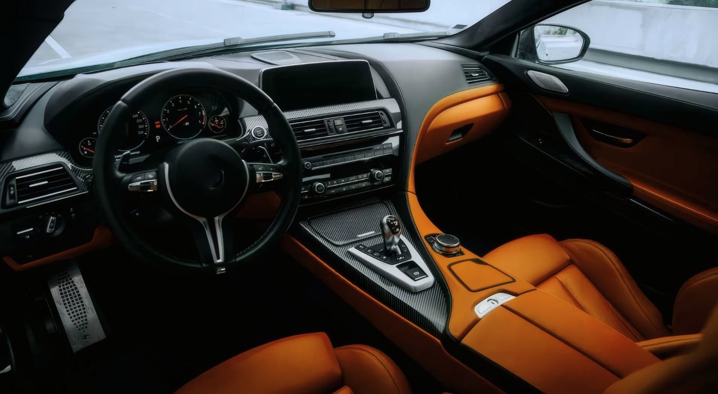 A steering wheel and orange leather seats