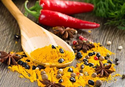 Turmeric on a wooden spoon with chillies