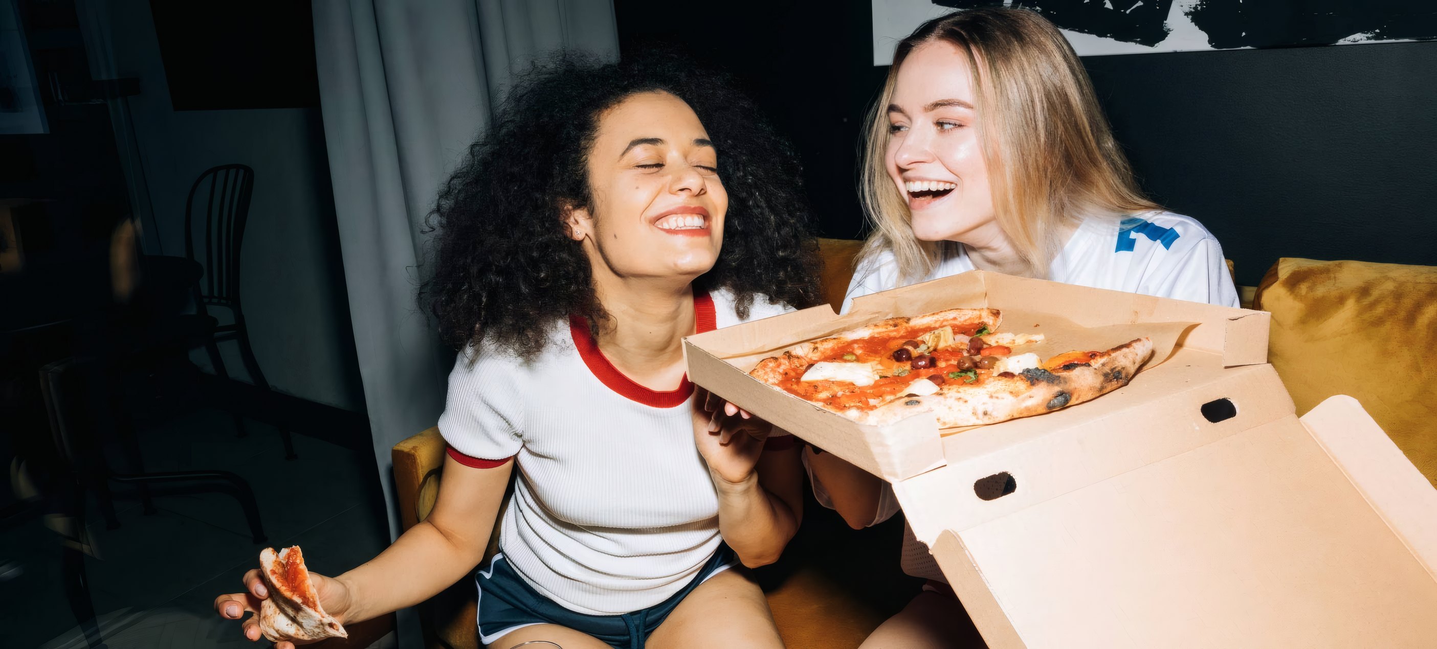 Two friends opening a pizza box late at night